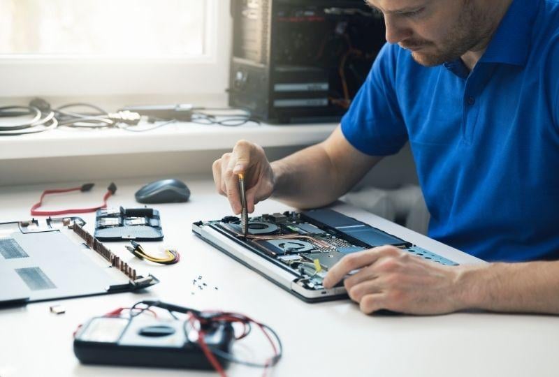 a computer repair technician working on a laptop