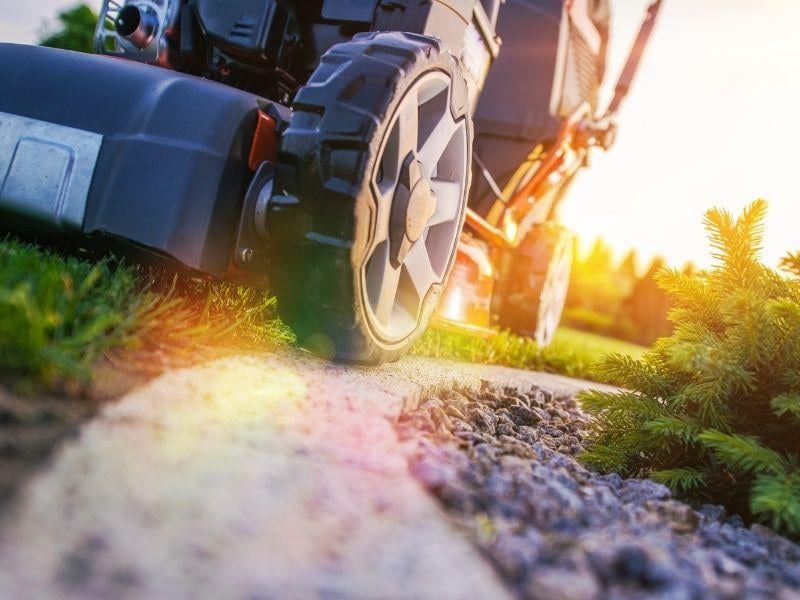 lawn care employee mowing grass for a customer