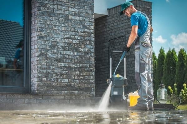 a technician power washing cement