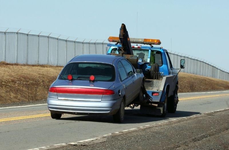 a sedan being towed by a tow truck company