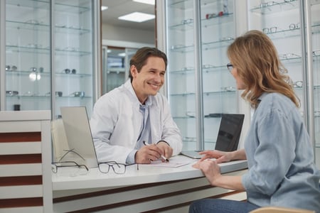 Optometrist collecting a credit card payment from a female patient