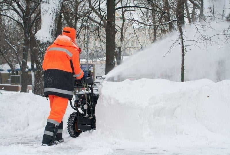 a man snow plowing a drive way