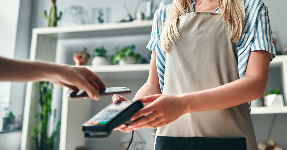 Woman holding a credit card terminal for a customer making a mobile wallet payment