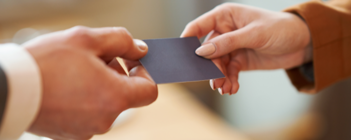 A person handing a credit card to another person while discussing credit card processing fees.