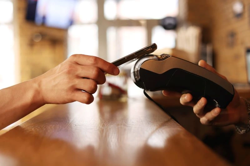 A person paying a POS transaction on a terminal inside of a store. 