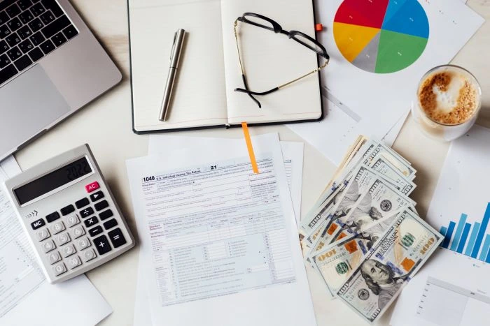 A tax form with money and a calculator on a desk after a merchant finds out what is an ein number. 