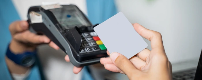 Hand holding credit card to pay at a terminal representing what is emv